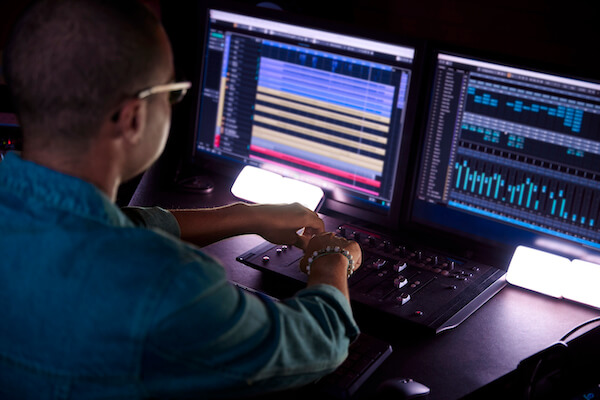 African-american man hipster producer working on music track on sound mixer control panel in professional music studio