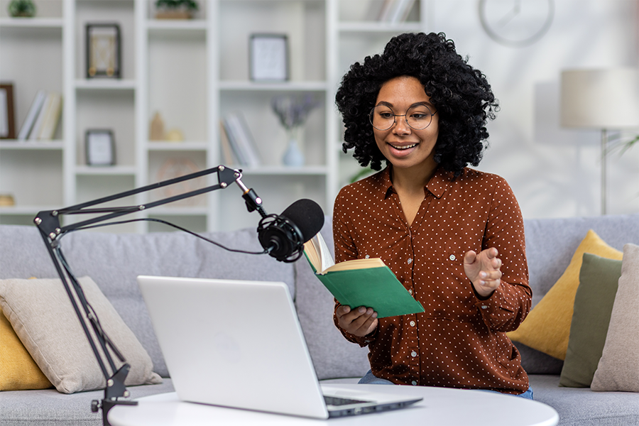 A woman wearing a brown button-up reviewing a book on a podcast filmed in her living room